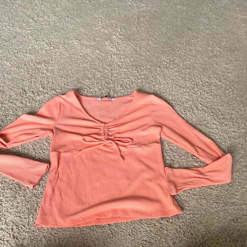 A coral pink long sleeve with a bow in the middle